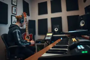 Musiker am Heimstudio-Schreibtisch mit Audio-Interface, Kopfhörern und Gitarre bei der Online-Arbeit