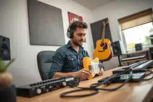 Musiker am Heimstudio-Schreibtisch mit Audio-Interface und Kopfhörern für die Musikproduktion zu Hause